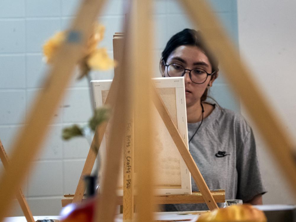 A student painting on an easel during an art class.