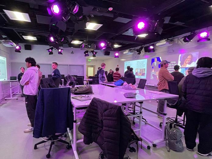 Students standing a looking at screens in a technology classroom