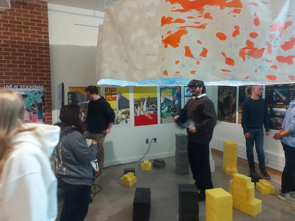 A group of students in an art gallery exploring installations including one student with a VR headset on. 