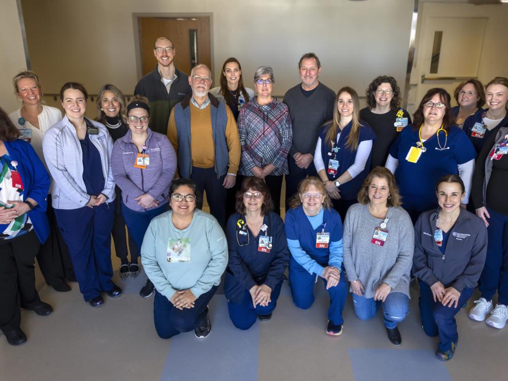 Twenty-one people pose for a photo in a hospital hallway.