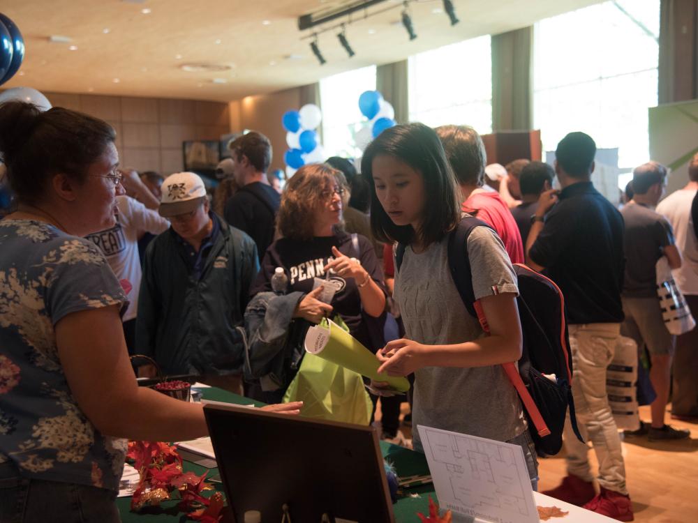A student reading information at a table during a housing fair.