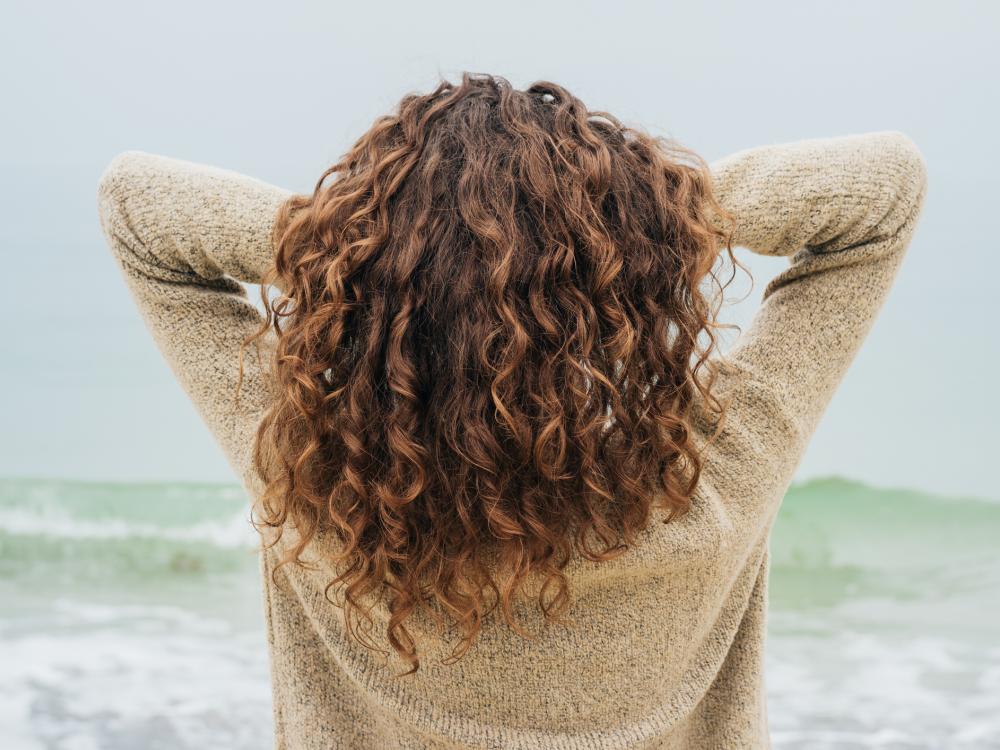 A woman with curly brown hair facing the sea