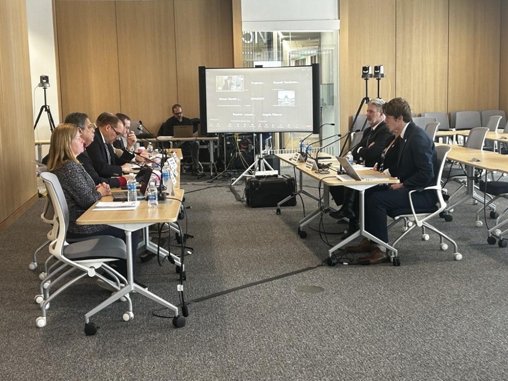 Attendees gathered around tables in a conference room, participating in a collaborative meeting or discussion.