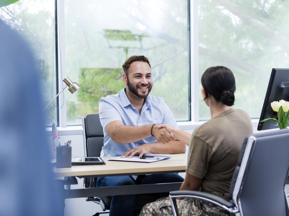 A soldier meets with the job recruiter to talk about employment options at a desk.