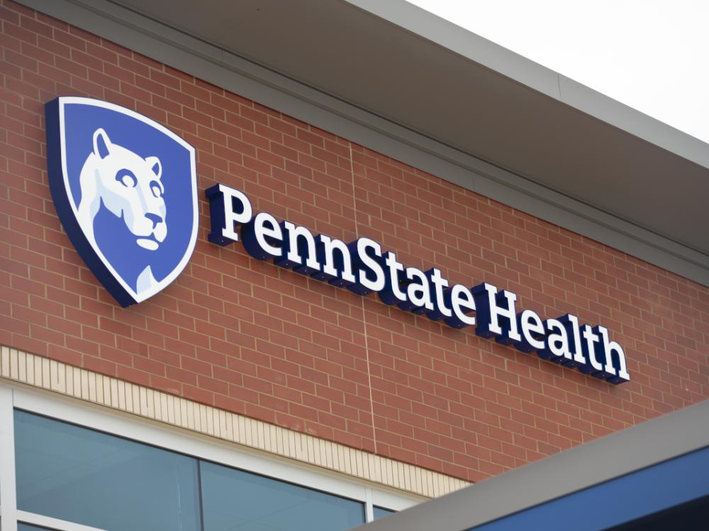A Penn State Health sign mounted on a red brick building.