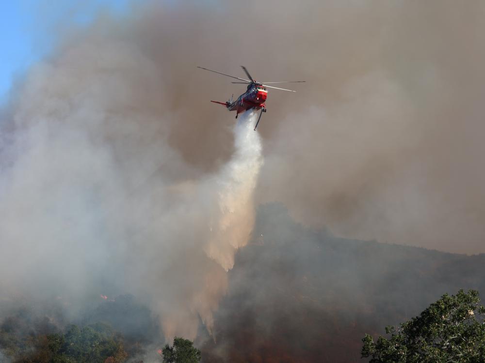 A helicopter drops water on a wildfire in Los Angeles in January 2025.