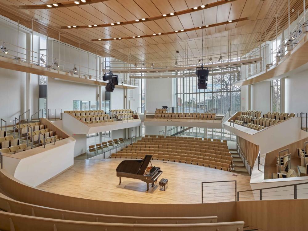 Recital Hall interior with empty audience seats and a piano on stage in the center