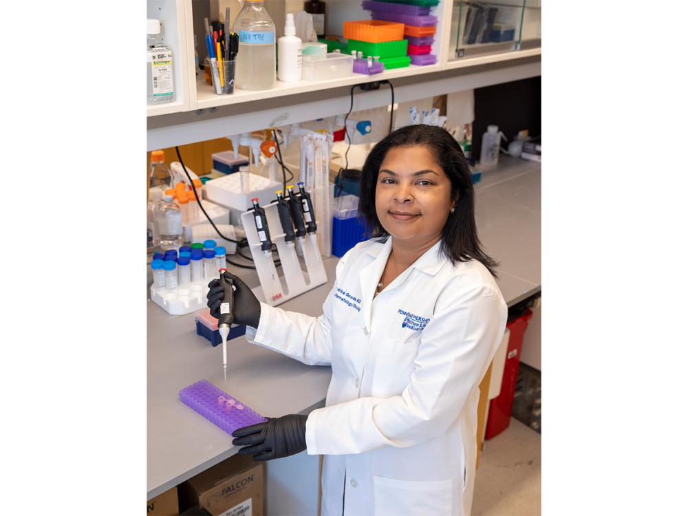 Scientist in a white lab coat holding a pipette