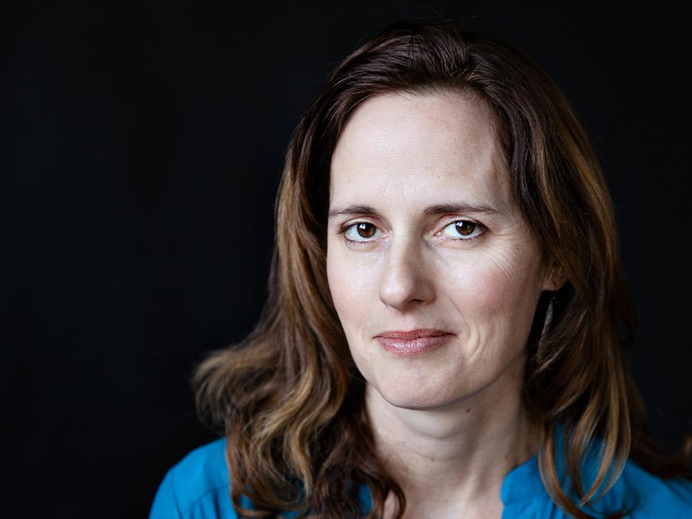 Headshot of a woman with dark hair and a blue shirt