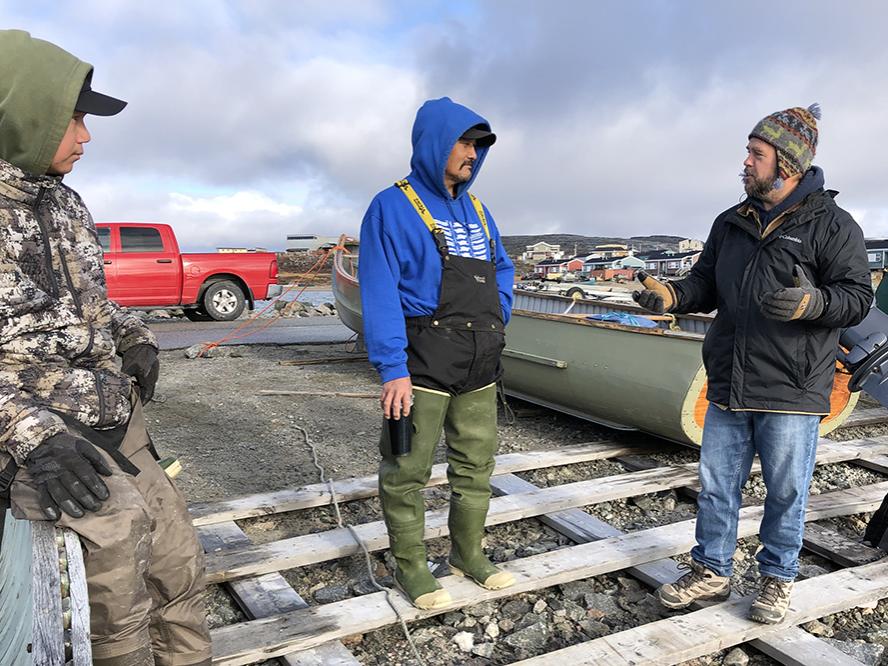 Kirk French talks with two hunters on the dock in Inukjuak before heading out on Hudson Bay.