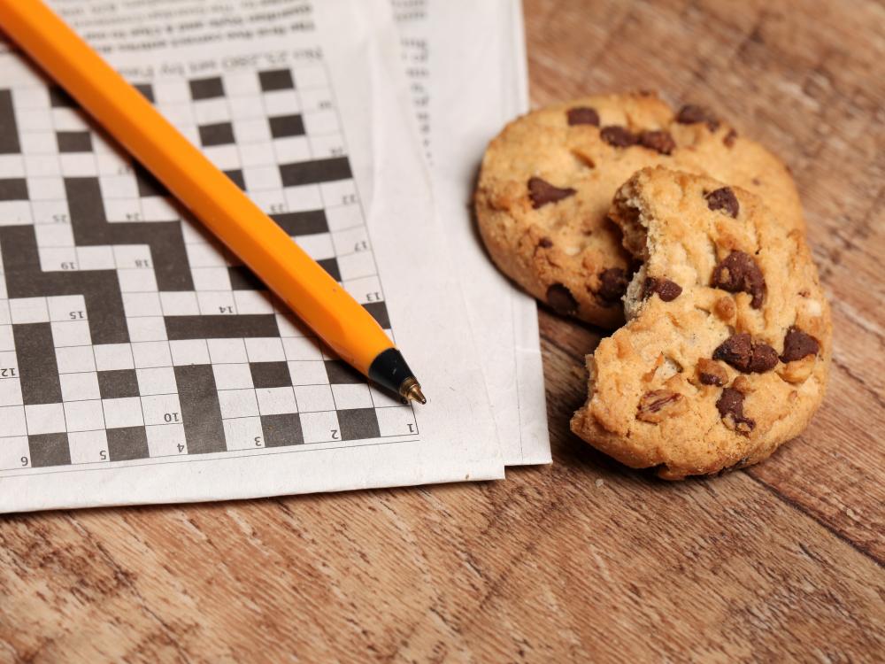 A crossword puzzle, pen and cookies on a wooden background