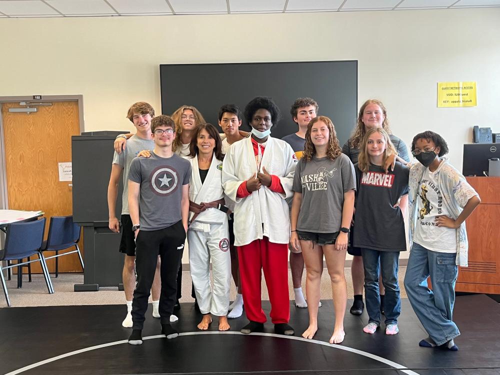 High school students posing for a photo in front of a chalk board in a classroom.