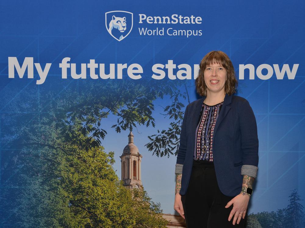 A woman poses in front of a Penn State-themed background.