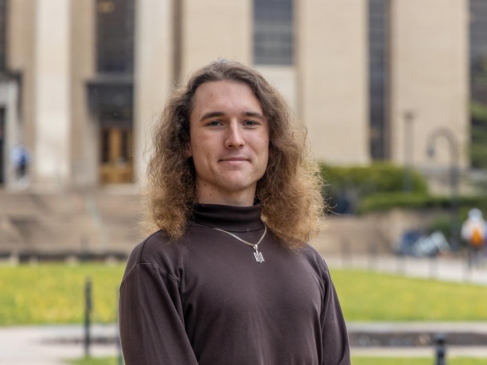 Igor Latsanych stands on Pattee Mall with Pattee Library and Paterno Library behind him.