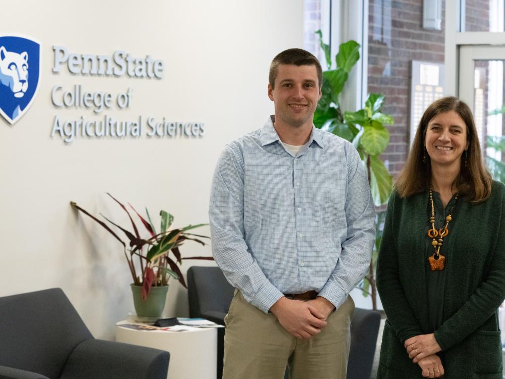 Two people stand in front of a wall that reads "Penn State College of Agricultural Sciences"