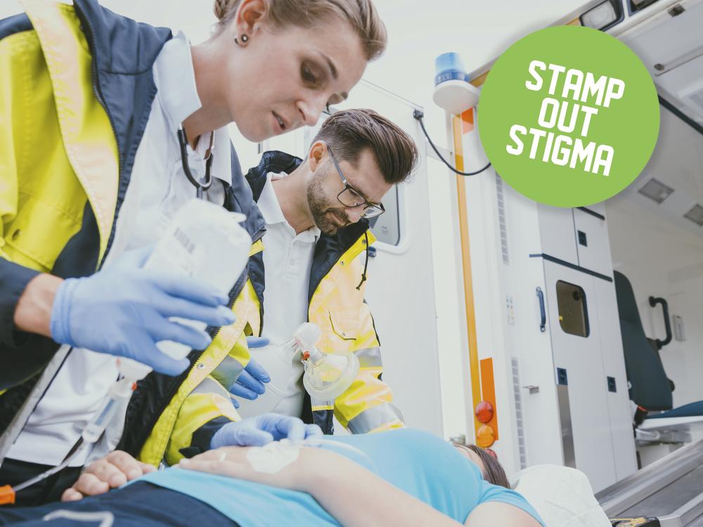 Two paramedics assisting a patient with text overlayed saying Stamp Out Stigma