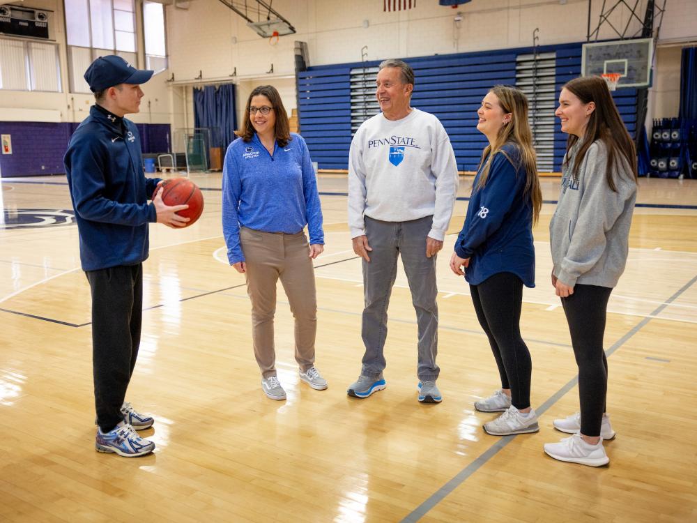 Five people standing on a basketball court