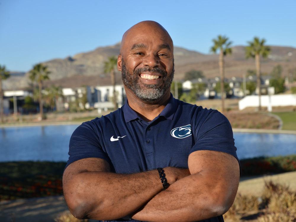Corey Wheeler stands with his arms crossed, a pond and palm trees in the background
