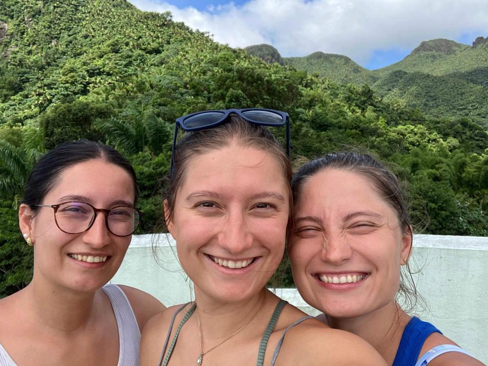 Maria Rebecca Duiker (left), Anna Raquel Duiker (middle) and Lina Ruth Duiker (right) pose for a selfie in front of tree-covered mountains in Puerto Rico.