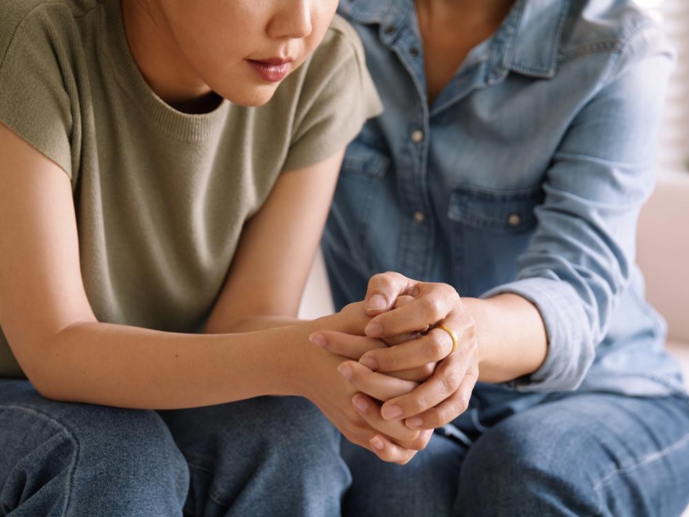 An older person holds hands with and comforts a younger woman