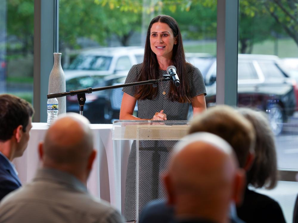 MBA alumna speaks at a podium in front of a group of people