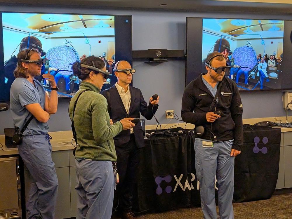 Neurosurgeons and neurosurgery residents wear headsets and hold remotes to take part in a mixed reality case review