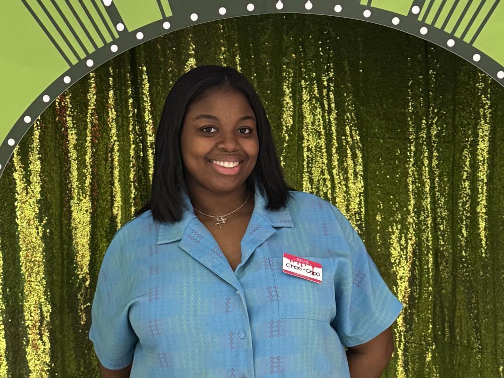 Charrise Lamothe poses for a photo in front of a green curtain