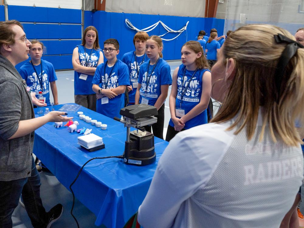A group of people stand talking around a table