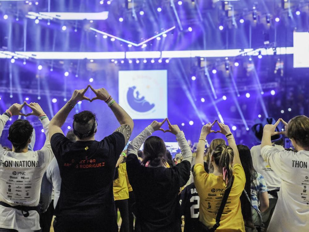 Scranton THON dancers face the stage and make the Four Diamonds symbol with their hands