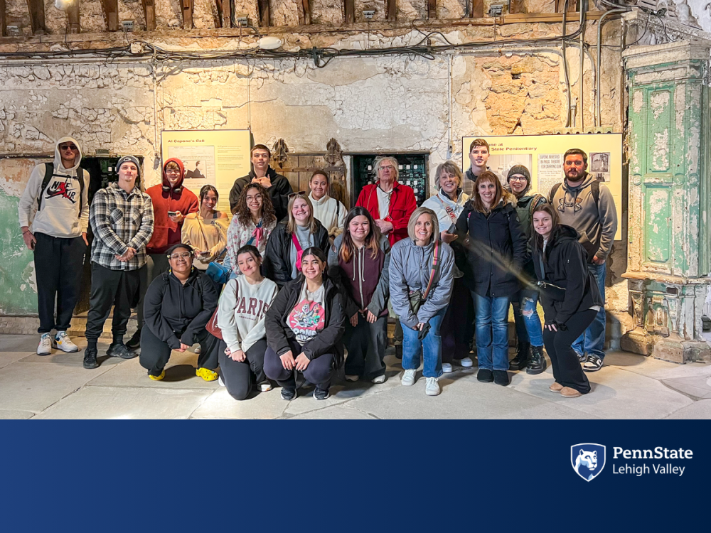 a group of students and teachers smile as a group while touring an old prison