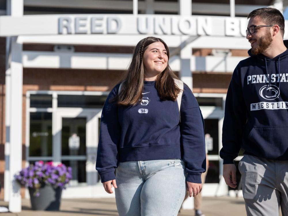 Two students smile while walking outside Penn State Behrend's Reed Union Building.