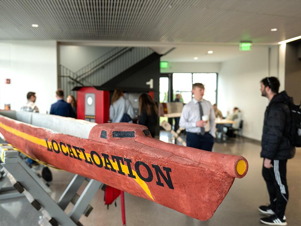 A boat in the foreground of people talking in a building