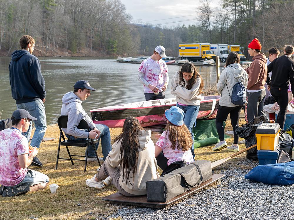 A group of people sit outside and talk at the Stone Valley Recreation Area in front of a concrete boat.