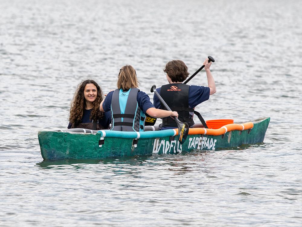 A group of people float on a lake in a concrete canoe.