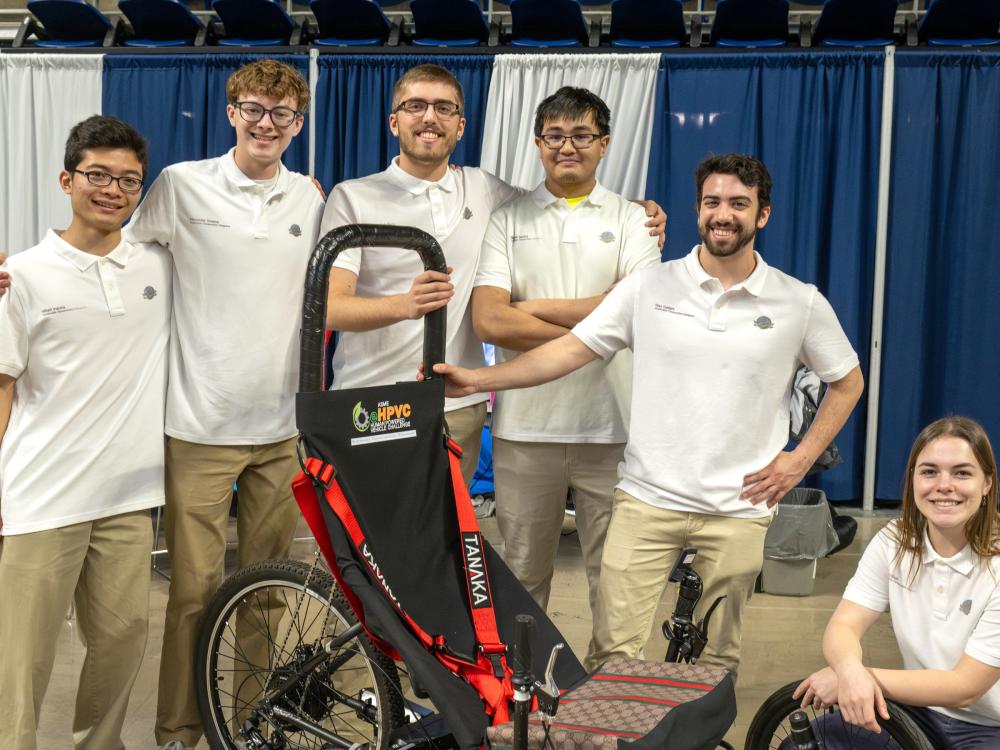 A group of students pose with their project in the Bryce Jordan Center.