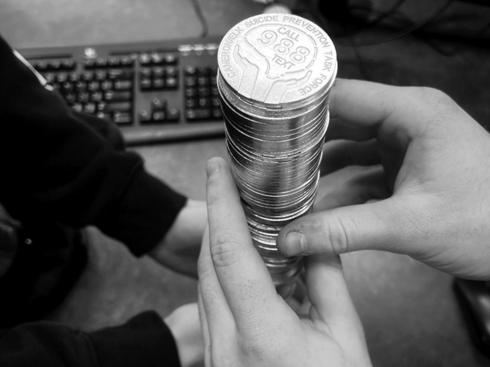 Two pairs of hands handle a stack of "988 coins"