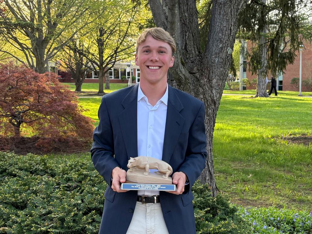 Student Arch Ackley poses with his Walker Award statue