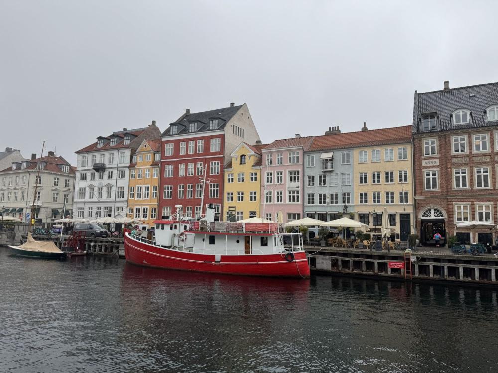 a view of copenhagen, denmark, from a canal with a boat in front of the pier.