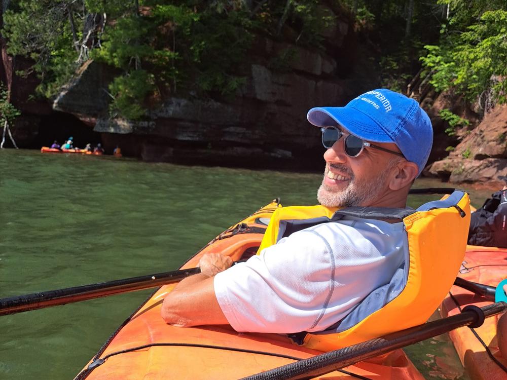 John Dattilo floating in a kayak on a lake with a cliff in the background