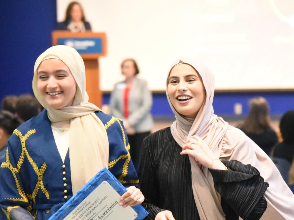 Two women in headscarves carry an award plaque at the Penn State Behrend Excellence in Leadership and Service Awards
