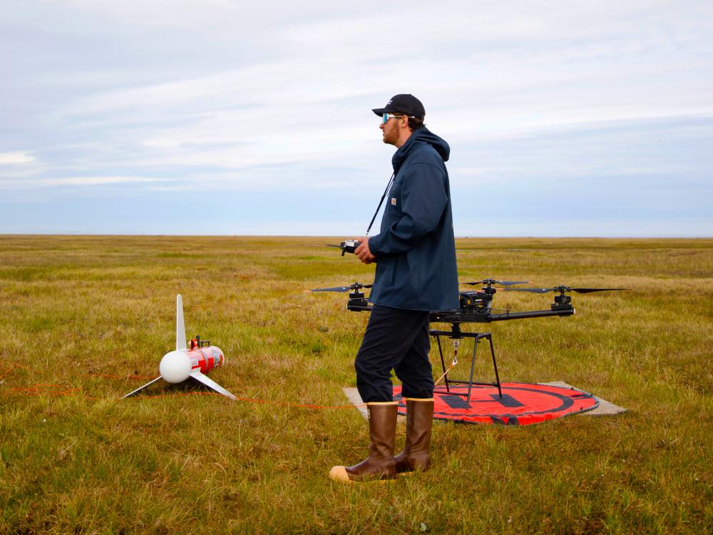 person standing next to drones in field