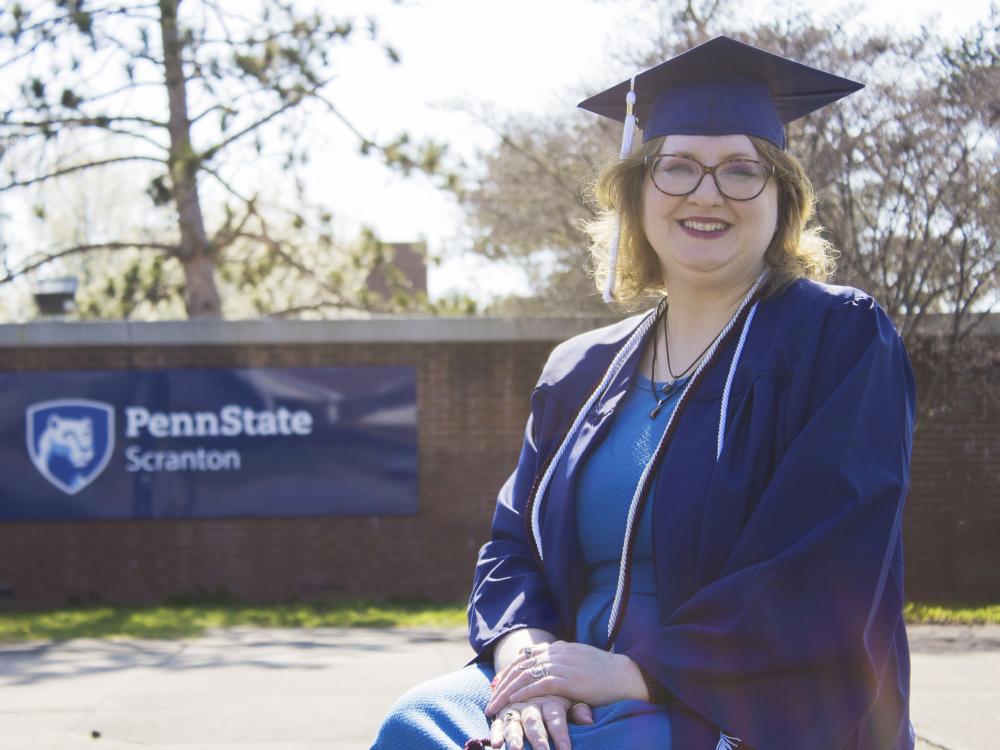 Student wearing commencement regalia and smiling