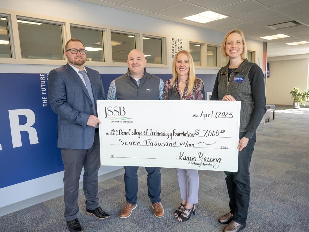 A group of smiling people pose with a big check
