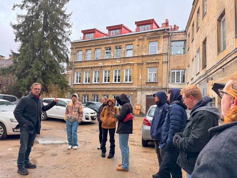 Tobias Brinkmann (left) talks to his students in front of him while standing in a parking lot outside a building in the former ghetto in Vilnius, Lithuania.