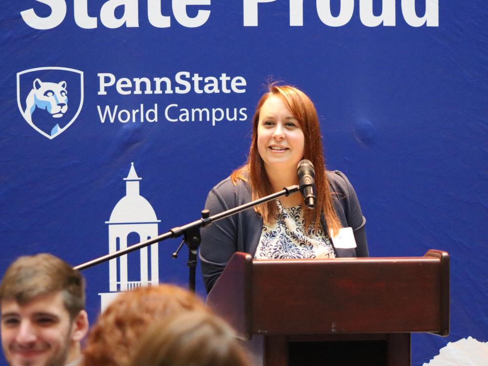 Marly Doty stands at a podium announcing an award winner.