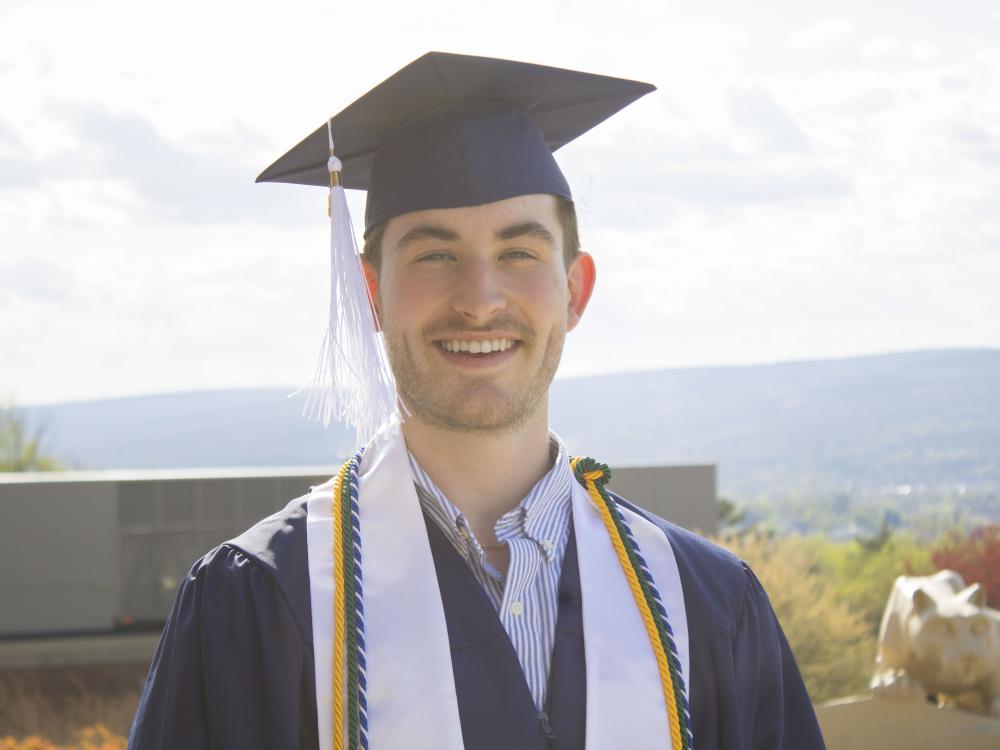 Student wearing commencement regalia and smiling