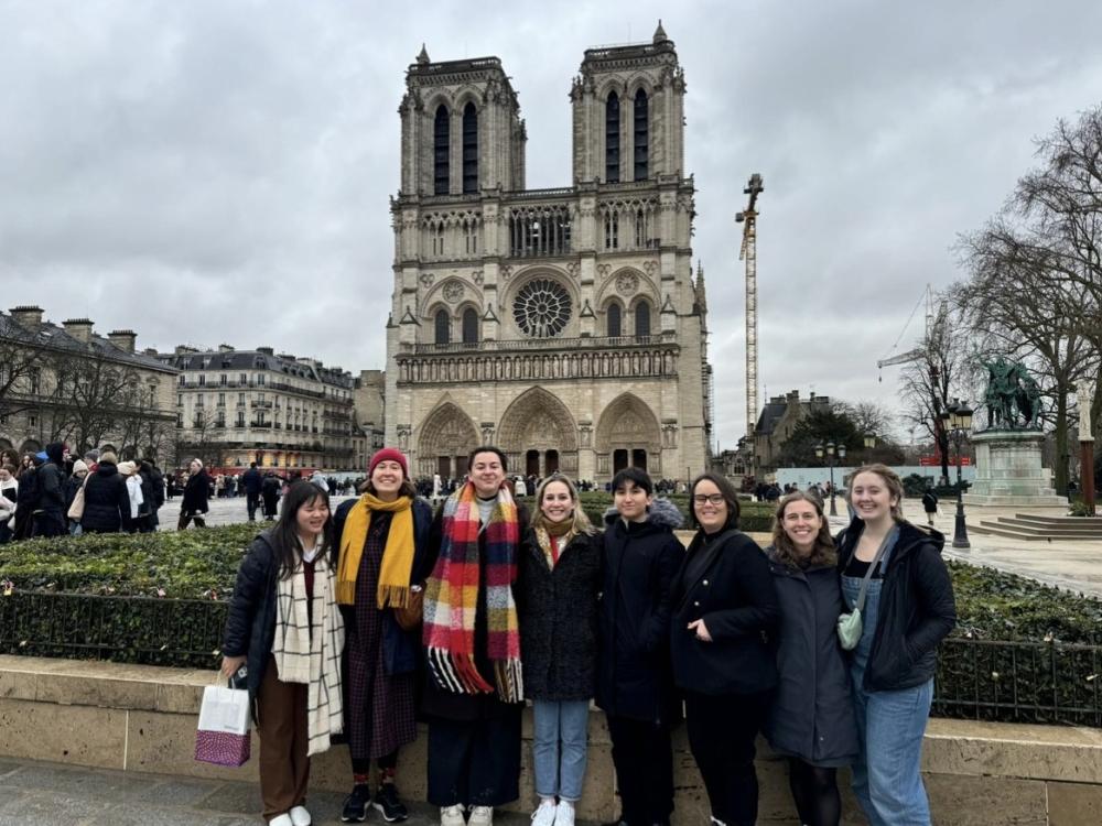 A group of college students gather in front of a cathedral
