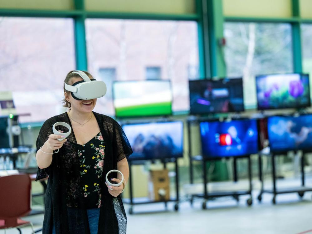 A woman experiments with VR while wearing a headset and holding two controllers.