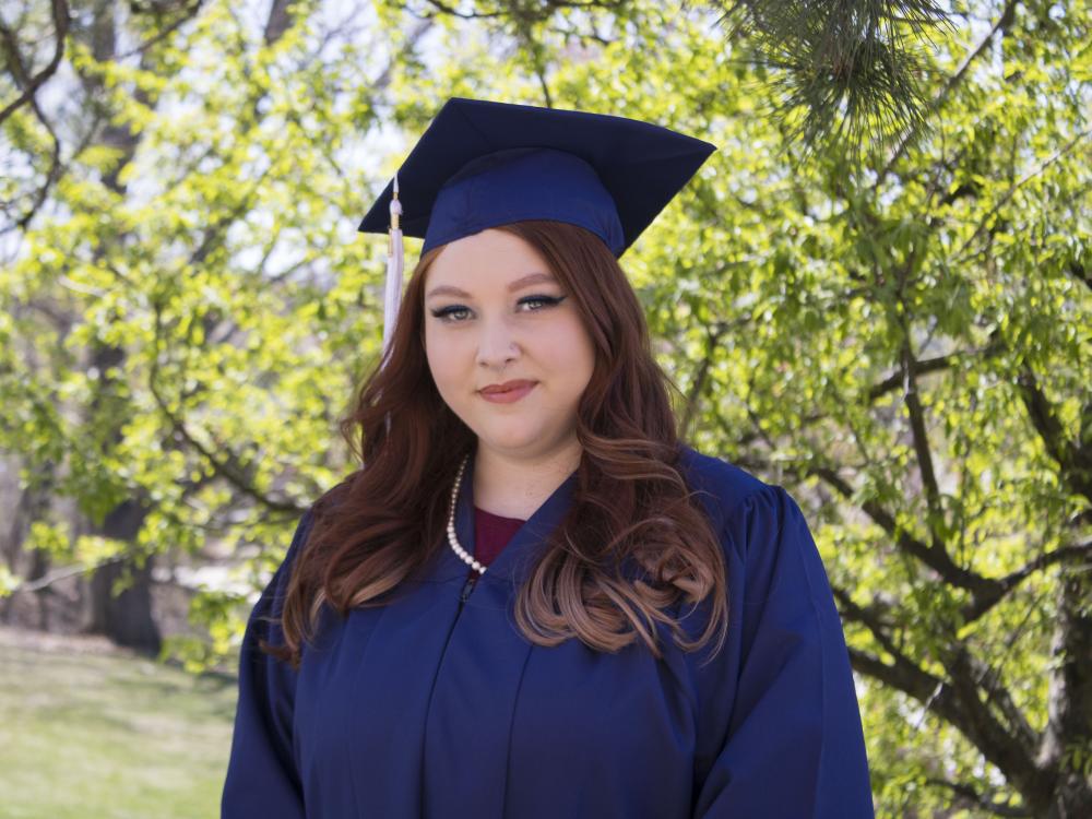 Student wearing commencement regalia and smiling
