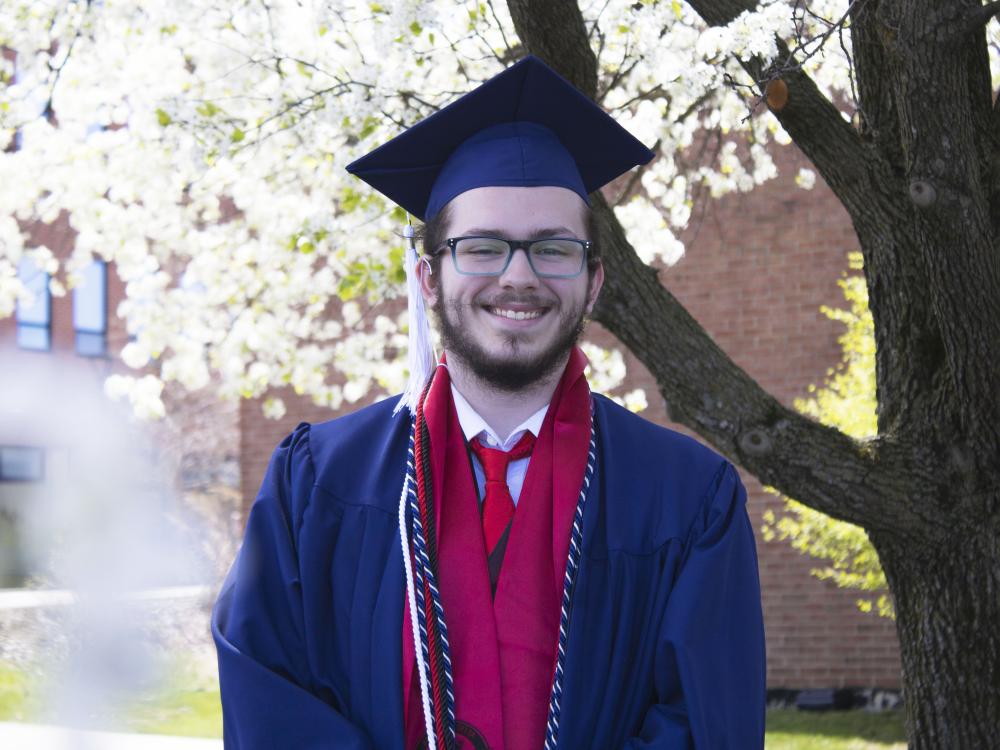 Student wearing commencement regalia and smiling